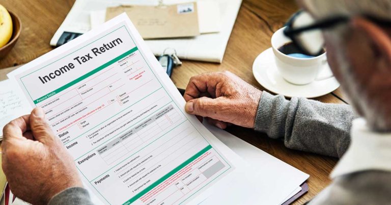 Elderly man looking over a printed out tax document